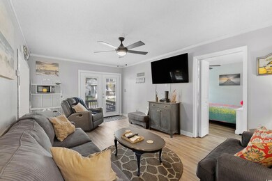 Living room with ceiling fan, light wood-style floors, crown molding, and french doors
