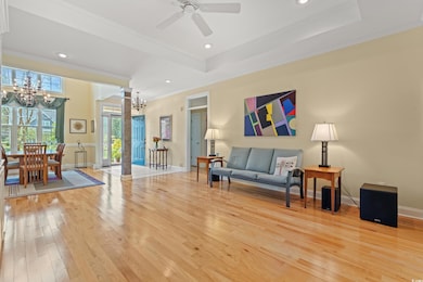 Living room with a raised ceiling, ornamental molding, hardwood / wood-style floors, recessed lighting, and a chandelier
