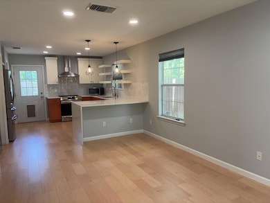 Kitchen featuring wall chimney exhaust hood, appl