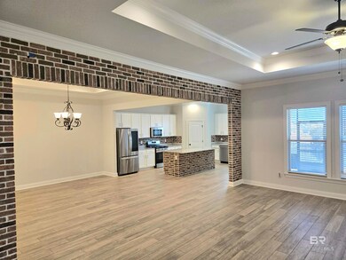 Kitchen with a raised ceiling, ornamental molding, a kitchen island, white cabinets, and open floor plan