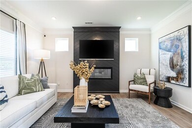 Living area featuring wood finished floors, a fireplace, baseboards, crown molding, and recessed lighting