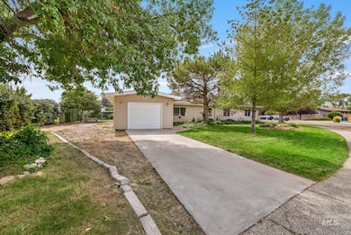 Ranch-style home featuring concrete driveway, an attached garage, and a front lawn