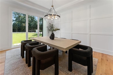 Dining room with a decorative wall, a chandelier, healthy amount of natural light, light wood-style flooring, and a tray ceiling