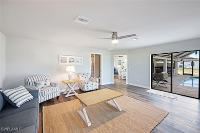 Living room with visible vents, ceiling fan, wood