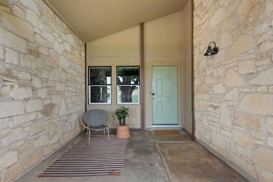 Entrance to property with stone siding and covere