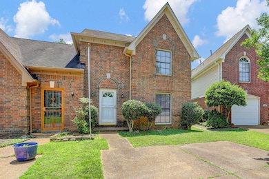 Traditional-style home featuring roof with shingles, a front yard, an attached garage, and brick siding