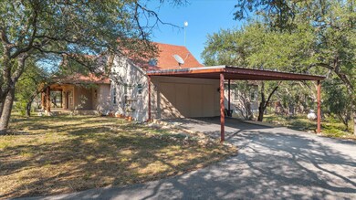 View of side of home featuring driveway, a carport, and a lawn