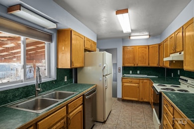 Kitchen with range with electric cooktop, brown cabinetry, and dark countertops