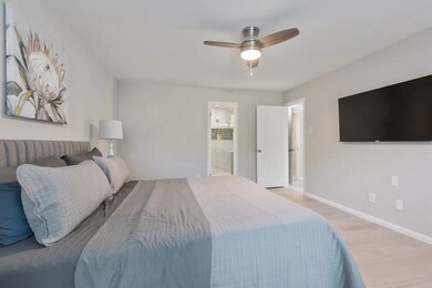 Bedroom featuring ensuite bath, light wood-style flooring, and a ceiling fan