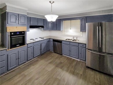 Kitchen with stainless steel appliances, pendant lighting, dark wood-style flooring, under cabinet range hood, and light stone counters