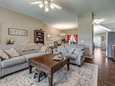 Living room featuring ceiling fan, wood finished floors, a chandelier, and baseboards
