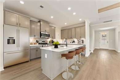 Kitchen with a breakfast bar, a kitchen island with sink, sink, light hardwood / wood-style flooring, and appliances with stainless steel finishes