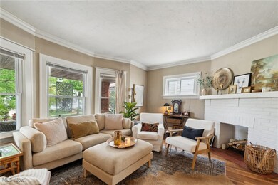 iving room with a fireplace, ornamental molding, and hardwood flooring