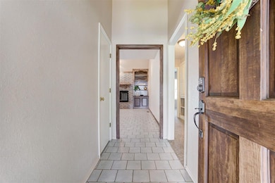Entryway with light tile patterned flooring and a textured wall