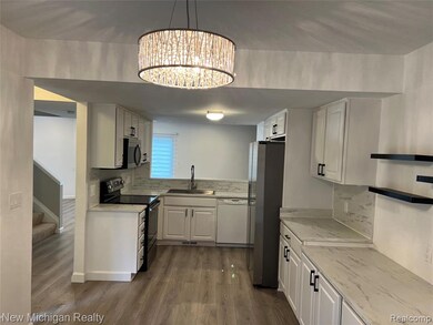 Kitchen featuring stainless steel appliances, white cabinets, dark wood-type flooring, and pendant lighting