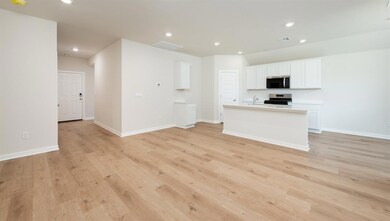Kitchen with recessed lighting, an island with sink, white cabinets, light countertops, and stainless steel appliances