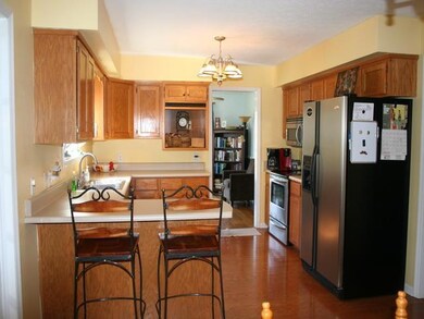 Large eat in kitchen with shiny stainless appliances, oak cabinets, lots of counter/storage space, and bar eating area.