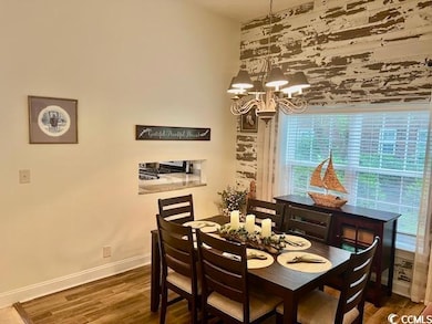 Dining room with healthy amount of natural light, baseboards, a chandelier, and wood finished floors