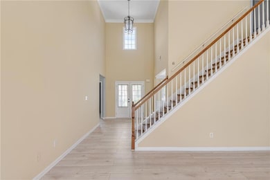 Entrance foyer with stairway, wood finished floors, crown molding, baseboards, and a towering ceiling