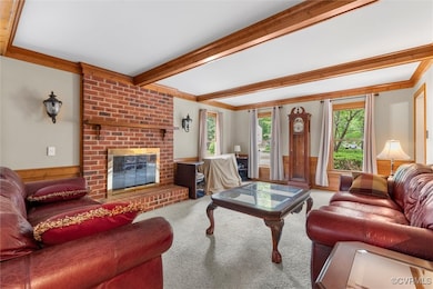 Living area with carpet floors, beam ceiling, a fi