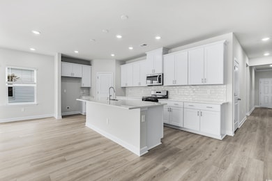 Kitchen featuring white cabinetry, tasteful backsp