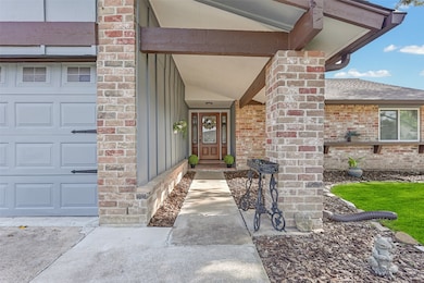 This inviting home features a charming brick exterior with a welcoming front porch and well-maintained landscaping. The entryway leads to a classic wooden front door, offering a perfect blend of modern and rustic appeal.