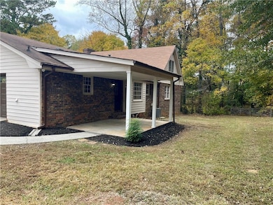 View of side of property featuring a lawn, brick siding, and roof with shingles