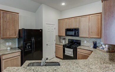 Kitchen with black appliances, a sink, light ston