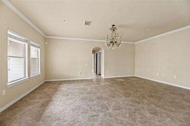 Spacious living area with elegant tile flooring, abundant natural light from large windows, and a stunning chandelier. Perfect for entertaining and relaxation.