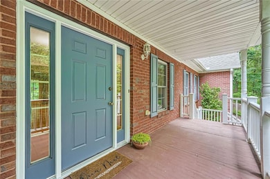 Property entrance featuring covered porch and brick siding