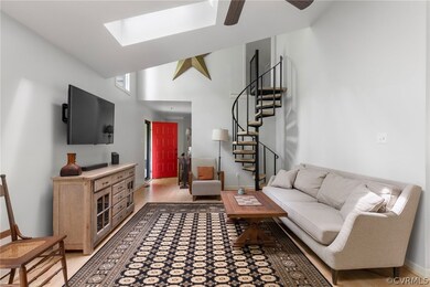 Living room featuring a skylight, light hardwood / wood-style flooring, ceiling fan, and high vaulted ceiling