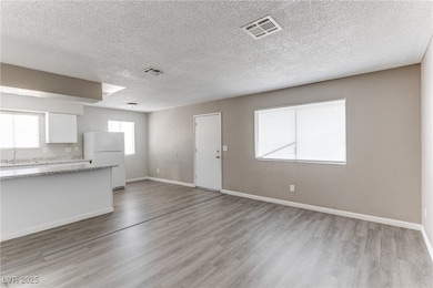 Unfurnished living room with light wood finished floors and a textured ceiling