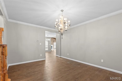 Unfurnished dining area featuring a chandelier, crown molding, and dark wood-style floors