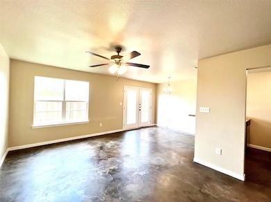 Empty room with concrete floors, a ceiling fan, a chandelier, french doors, and a textured ceiling
