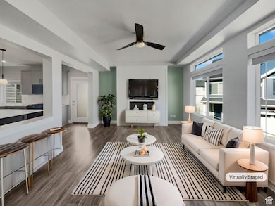 Living room featuring plenty of natural light, baseboards, wood finished floors, and a ceiling fan
