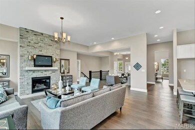Living room with dark wood-style floors, a chandelier, recessed lighting, and a stone fireplace