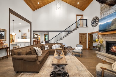 Living area with high vaulted ceiling, recessed lighting, dark wood-style flooring, a fireplace, and stairway