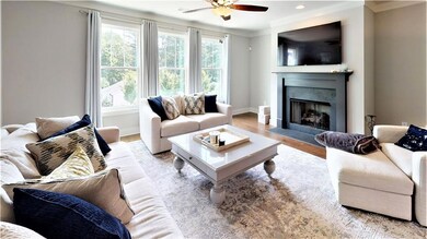 Living area featuring a ceiling fan, a fireplace with flush hearth, crown molding, wood finished floors, and recessed lighting