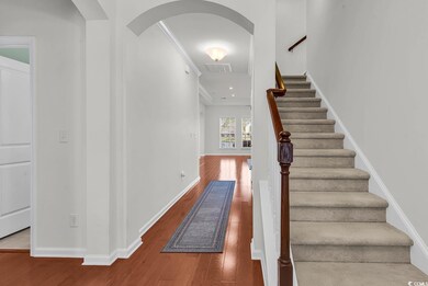 Staircase featuring arched walkways, wood finished floors, baseboards, and ornamental molding