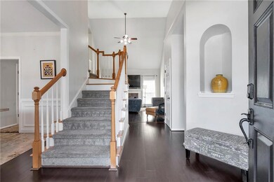 Foyer entrance with hardwood / wood-style floors, stairway, ceiling fan, and a fireplace