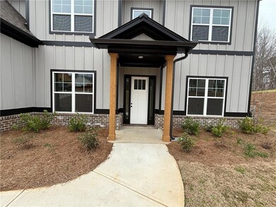 View of exterior entry featuring brick siding and board and batten siding, covered entrance