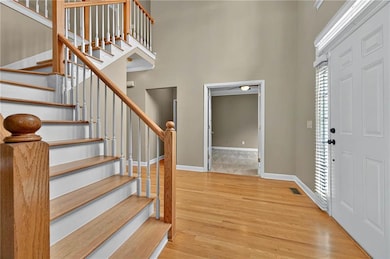 Foyer entrance featuring wood finished floors, baseboards, stairway, and a high ceiling