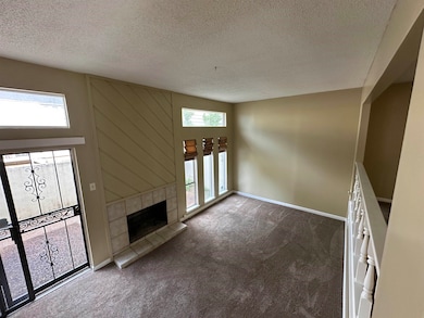 Unfurnished living room featuring carpet floors, a textured ceiling, and a tiled fireplace