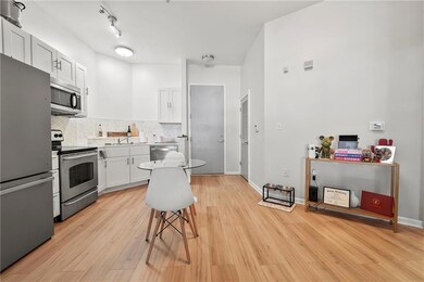 Kitchen with appliances with stainless steel finishes, light wood-style flooring, white cabinetry, tasteful backsplash, and a kitchen breakfast bar