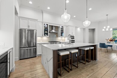 Kitchen featuring tasteful backsplash, wine cooler, appliances with stainless steel finishes, crown molding, and wall chimney range hood