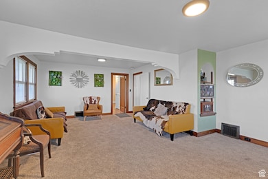 Living area featuring carpet floors, arched walkways, and visible vents