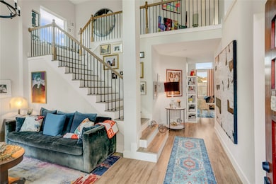 Open living area with soaring ceilings, a sweeping staircase, and a bright, gallery-style hallway that pulls the eye straight through the main level. Warm wood floors, layered textures, and thoughtful lighting make the space feel inviting and elevated at the same time.