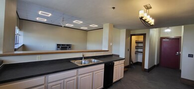 Kitchen with dark countertops, a drop ceiling, decorative light fixtures, and white cabinetry