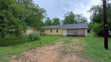 Rear view of house with a yard and dirt driveway