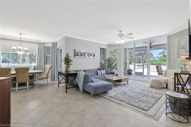 Living area with ornamental molding, a chandelier, ceiling fan, light tile patterned floors, and plenty of natural light